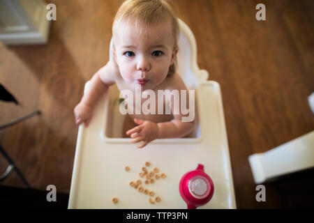 High angle view of baby girl eating snack à la maison. Banque D'Images