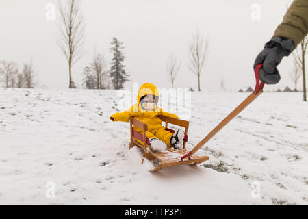 Mère fille bébé tire sur le traîneau en bois après des chutes de neige. Banque D'Images