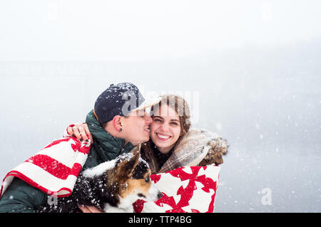 Jeune couple blottis dans le contrat cadre avec chien de neige Banque D'Images