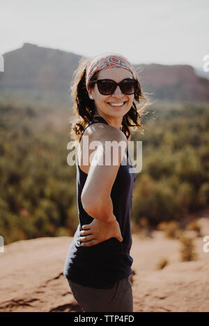 Smiling young woman standing on top of rock contre montagne Banque D'Images