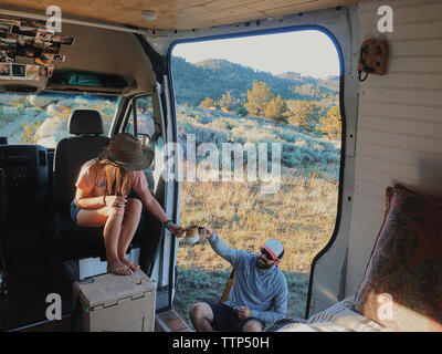 High angle view of couple toasting drinks while sitting in motor home à forest Banque D'Images