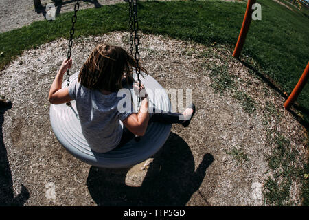 Portrait de fille se balançant à l'aire de jeux Banque D'Images