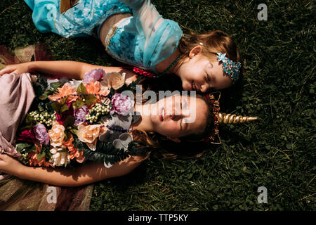 Portrait de sœurs dans Halloween costumes lying on grassy field in park Banque D'Images