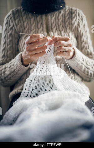 Midsection of woman knitting at home Banque D'Images