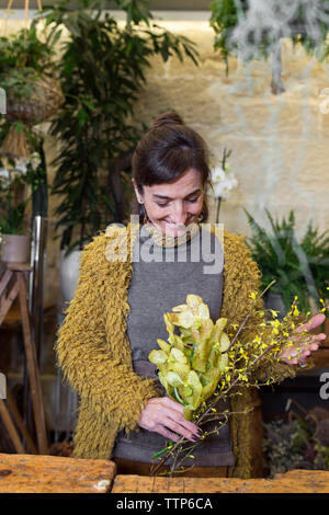 Portrait of cheerful woman holding fleurs jaunes à shop Banque D'Images