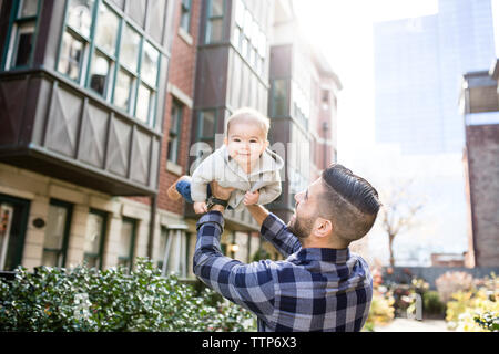 Smiling dad et le bébé à l'extérieur de la ville en tenant bébé Banque D'Images