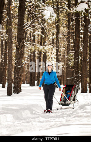 Femme heureuse avec son traîneau en marche sur champ neigeux Banque D'Images