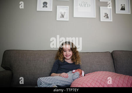 Portrait of cheerful girl avec sœur sitting on sofa at home Banque D'Images