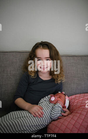 Portrait of smiling girl avec sœur sitting on sofa at home Banque D'Images