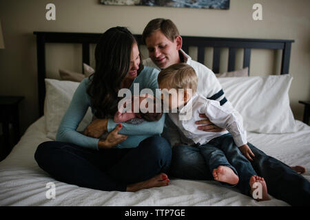Famille avec le nouveau-né baby boy sitting on bed at home Banque D'Images