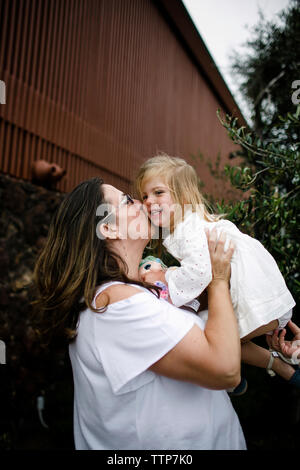 Happy mother kissing fille debout au centre touristique Banque D'Images