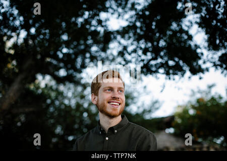 Low angle view of thoughtful man à la route en position debout contre des arbres au parc Banque D'Images