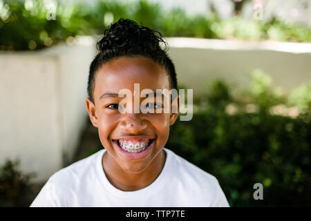 Close-up portrait of smiling boy standing at park Banque D'Images