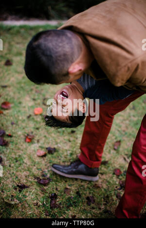 High angle view of playful père exerçant son fils heureux en se tenant sur le terrain d'herbe dans le Parc Balboa Banque D'Images