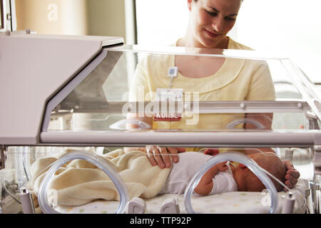 Nurse touching baby girl lying in Incubator at hospital Banque D'Images