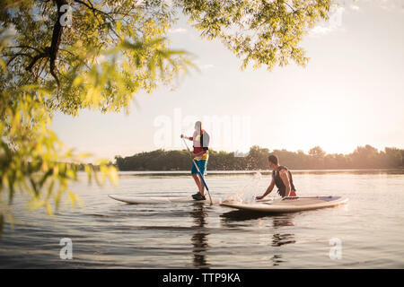 Fils ludique aux projections d'eau sur le père avec rame sur le lac Banque D'Images
