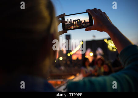 Rear view of woman photographing Brooklyn Bridge au coucher du soleil Banque D'Images