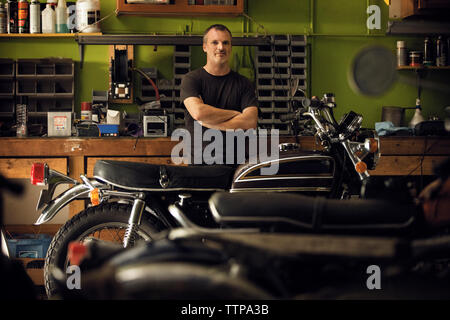 Portrait of owner standing en moto en atelier Banque D'Images