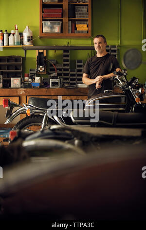 Portrait of owner standing en moto en atelier Banque D'Images