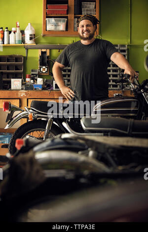 Portrait of owner standing en moto en atelier Banque D'Images