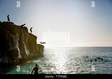 Les amis sauter de falaise de mer contre sky