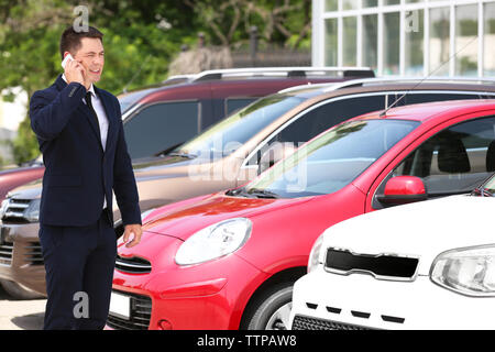 Man talking on phone sur les nouvelles voitures background Banque D'Images