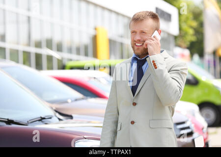 Man talking on phone sur les nouvelles voitures background Banque D'Images