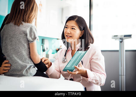 Femme médecin montrant part x-ray sur tablet computer to girl in clinic Banque D'Images