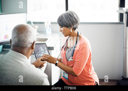 Femme médecin expliquant à rayons x sur le patient dans la clinique de l'ordinateur tablette