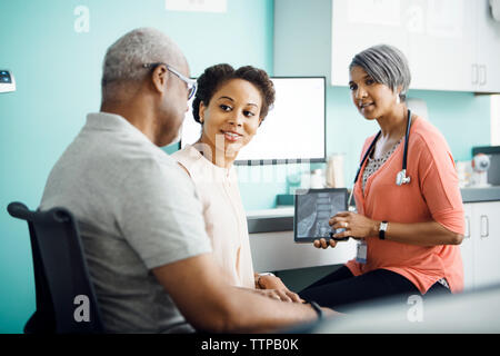 Fille de parler à son père alors qu'il était assis avec femme médecin en clinique Banque D'Images