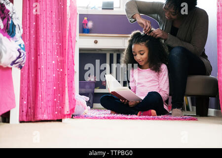 Woman combing daughter's hair at home Banque D'Images