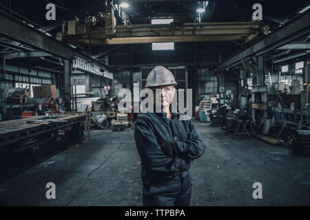 Portrait of female worker with arms crossed standing in factory Banque D'Images