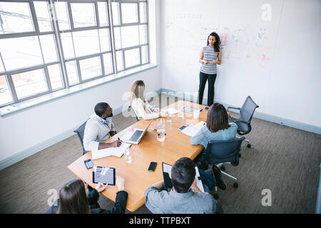 High angle view of businesswoman expliquant les données pendant l'article tableau blanc dans la salle du conseil par Banque D'Images