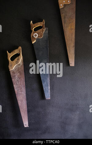 Old rusty scies à main accroché au mur Banque D'Images