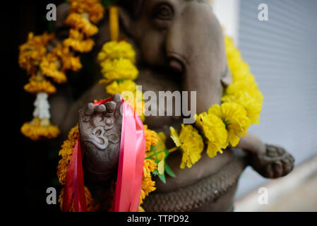 Close-up of Om signe sur main de Ganesha statue avec guirlande de fleurs Banque D'Images