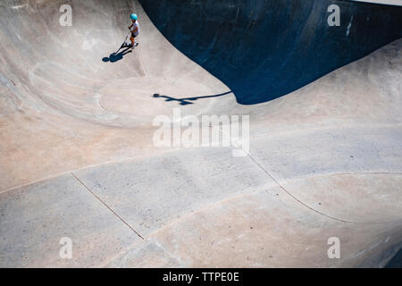 High angle view of girl riding scooter push sur rampe à sports park Banque D'Images