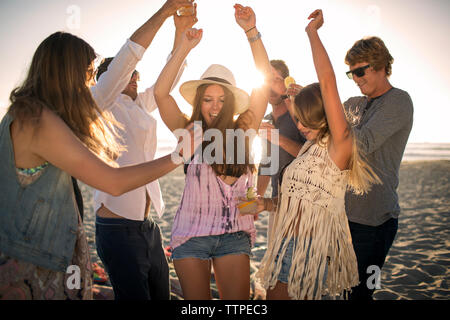 Cheerful friends dancing on beach Banque D'Images