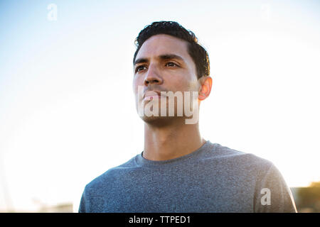 Low angle view of thoughtful male athlete contre ciel clair Banque D'Images