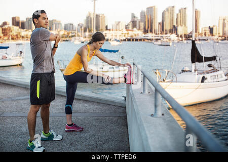 Les athlètes masculins et féminins de faire des exercices d'étirement sur la jetée par Harbour Banque D'Images