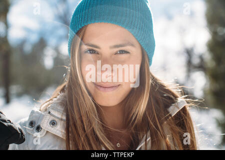 Portrait of smiling woman wearing Knit hat standing sur terrain au cours de l'hiver Banque D'Images