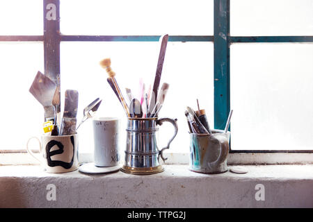 Pinceaux et d'outils en cup le rebord de fenêtre Banque D'Images