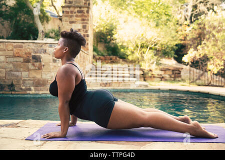 Voir le profil de déterminé woman doing push-ups sur mat at poolside Banque D'Images