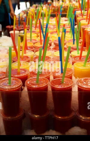 Jus d'orange et jus de fraises dans des tasses en plastique avec une paille en plastique de différentes couleurs sur le marché Banque D'Images
