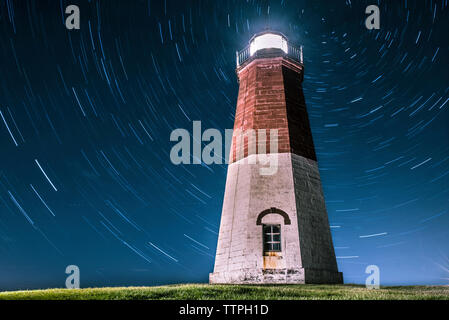 Low angle view of illuminated phare contre star trails de nuit Banque D'Images