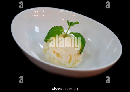 pelle à glace à la vanille au coeur de la feuille de menthe dans un bol, avec fond noir Banque D'Images