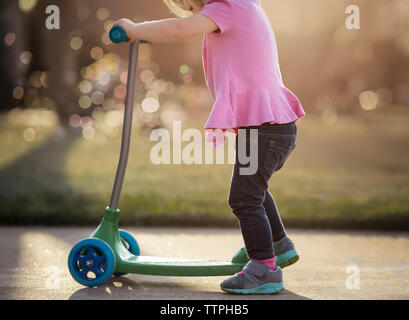 La section basse de girl riding scooter push sur sentier Banque D'Images