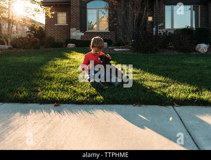 Boy Playing with dog on grassy field in backyard Banque D'Images