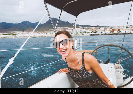 Smiling woman sitting in bateau naviguant sur la mer Banque D'Images