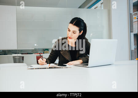 Young Hispanic Woman working on Laptop in Classroom Banque D'Images
