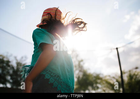 Low angle view of girl wearing hat bénéficiant en trampoline contre ciel lors de journée ensoleillée Banque D'Images